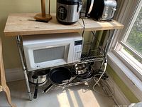 Kitchen island with light wood top and two metal wire shelves, holding kitchen items (not included). Light wear on wood surface.