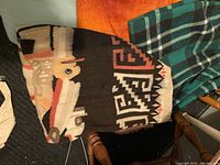 Wool blanket with Native American style geometric pattern and horse design, teal and black checkered wool blanket on chair