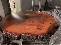 Solid wood round slab on metal shelving, showing top surface and edge