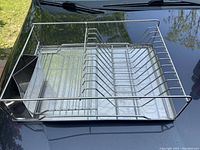 Top view of stainless steel dish strainer showing slots for plates and side compartment, sitting on a tray base.