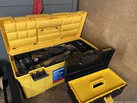 Yellow plastic Mastercraft tool box open with mixed tools including hammers, nails, screws inside