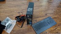 Fell D03S computer tower standing vertically with attached cables and headphones resting beside, Logitech keyboard on floor