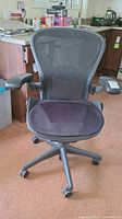 Front view of black Aeron office chair showing mesh back, seat cushion and five-star caster base.