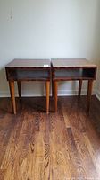 Pair of matching walnut wood end tables showing front and top views with pass-through open shelf sections under rectangular tops on cylindrical legs.