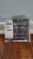 Clear plastic bag with visible Henry’s gift cards and handwritten lot number label