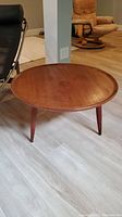 Angled front view of round teak side table showing top surface and tripod legs