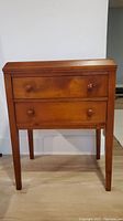 Front view of wooden side table showing two drawers with wooden knobs.