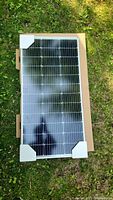 Full front view of the solar panel in its original packaging, showing protective foam corners
