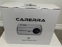 Front view of Carerra 8K Smart Projector sealed in original white box with product image and branding.