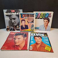 Five Elvis Presley collectible items: two hard cover books and three magazines, arranged and showing front covers