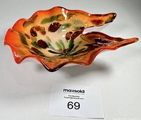 Art glass bowl with red/orange and gold sparkle, white cased base, photographed from angle showing asymmetric shape and colors.