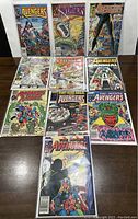 Collection of nine Avengers comic books and annuals arranged on a table, showing colorful front covers in plastic sleeves.