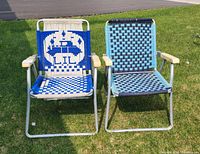 Two vintage aluminum framed chairs on grass, one with blue and white crab woven design, other with blue and black checkerboard.