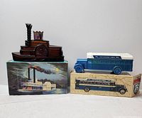 Two vintage Avon decanters, one shaped like a steamboat and one like a bus, displayed with original boxes