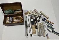 Overview photo showing the wooden box full of assorted vintage dental tools including metal dental files, hand instruments, and accessories mostly unboxed, with some in original teeth-cleaning tool packaging.
