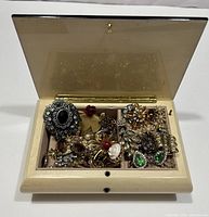 Overall view of the open jewelry box showing assorted brooches and earrings inside