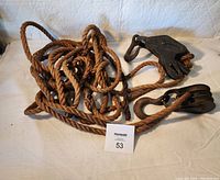 Full view of the vintage rope and cast iron pulley set showing the entire length of rope and both pulley units.