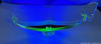 Gondola shaped uranium glass ashtray glowing green under UV light showing uranium glass effect.