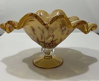 Front angled view of caramel colored Murano glass pedestal dish showing ruffled rolled edges and marbled caramel patterns.