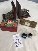 Wood and pewter bookends, metal bank with patriotic design, Florn folding clock, and two typewriter type balls in plastic cases laid out on white background.