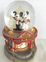 Full view of Disney snow globe with Mickey and Minnie Mouse figurines inside, detailed base with 'The Colony Theatre' signage and glitter inside globe.