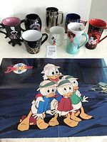 Front view of all eight Disney mugs arranged in two rows with DuckTales poster laid flat below them