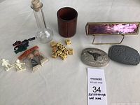 Full lot view showing kaleidoscope glass bottle, leather cup, dice, belt buckles, Kokeshi erasers, Van Brode figures, bottle, plastic horse.
