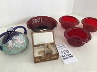 Overview photo showing four red glass bowls, textured squat vase, and box containing foo dog stamp.