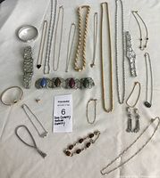 Overhead photo showing full assortment of jewelry laid out on white cloth, displaying various bracelets, necklaces, and earrings with a MaxSold lot label visible.