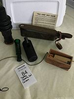 Photo of all five calls including the True Tone box call with strap, The Cheater box call, The Gobbler call, Power Owl, and Owl Hooter on a light fabric background.