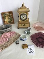 Wide view of lot showing all items including wooden clock, glass bowls, ceramic shoe vase, compact, doily, cement planter, small frame and more.