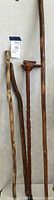 Photo showing four wooden walking sticks standing vertically, highlighting their varied shapes and sizes