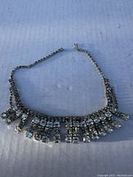Rhinestone necklace lying flat showing arrangement of stones and missing areas.
