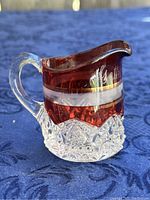 Photo showing front side of small ruby flash glass creamer pitcher with clear cut glass base and etched 'Gettysburg 1863' inscription.