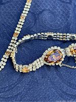 Close-up of necklace and earring showing citrine and clear rhinestone details, showcasing pear-shaped citrine centerpiece.