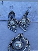 Silver-tone earrings showing front with faux pearl and rhinestone