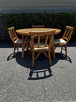 Full view of the Bradston MCM round rattan table and four chairs outdoors showing the style and condition.