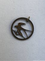 Close-up photo of the penny art sparrow pendant, showing the detailed carving of the bird within the penny edge and the bail attachment.