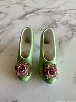 Top view of the pair of green bone china high heel shoes figurines showing pink rose decoration on toes and interior wear.