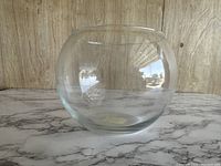 Front and side view of the vintage clear glass bubble round bowl on a marble surface, showing its round bubble shape and clarity.