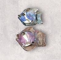 Front view of both iridescent fish wall plaques lying flat on a surface, showing blue and purple hues and textured details.