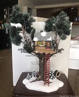 Front view of Dept. 56 Snow Village treetop tree house with original box in background