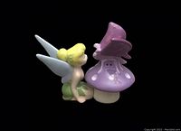 Single view of salt shaker Tinkerbell facing mushroom pepper shaker with butterfly on top under side lighting.