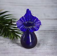 Front view of cobalt blue Jack-in-the-Pulpit art glass vase on a light surface with greenery in background.