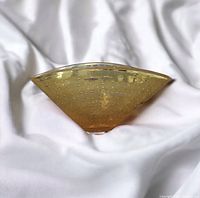 Yellow-tinted control bubble glass vase/bowl with Kosta Boda label on one side, placed on white fabric background.