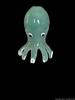 Front side view of the light green and white cased glass octopus figurine with eyes and tentacles detailed.