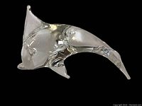 Clear art glass dolphin figurine shown from side angle highlighting shape and chip on fin.
