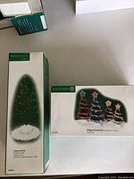 Closed box of Village Accessories Tinsel Trees showing image of 4 trees with star toppers in green, red, and gold colors.