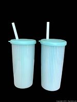 Two tall turquoise insulated Tupperware cups with matching lids and original white straws, ribbed texture on cups