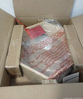 Photo of the hexagonal wood shelf packed inside a cardboard box with protective packaging visible.